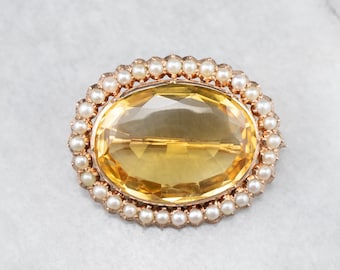 May include: A gold brooch with a large, oval-shaped, yellow citrine gemstone surrounded by a border of small, white pearls.