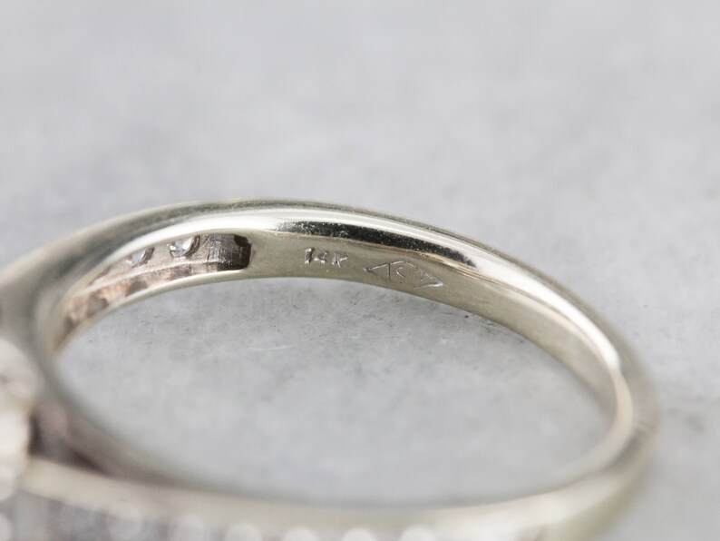 Puede incluir: Primer plano del interior de una banda de anillo, que muestra un sello de 14K y un peque&ntilde;o diamante engastado en la banda.