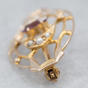 May include: A gold heart-shaped brooch with a purple gemstone and pearl accents.