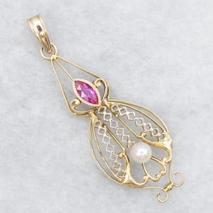 Puede incluir: Colgante de oro con una gema rosa talla marquesa y una perla redonda. El colgante tiene un diseño calado abierto con una fianza decorativa. El colgante es probablemente de oro.
