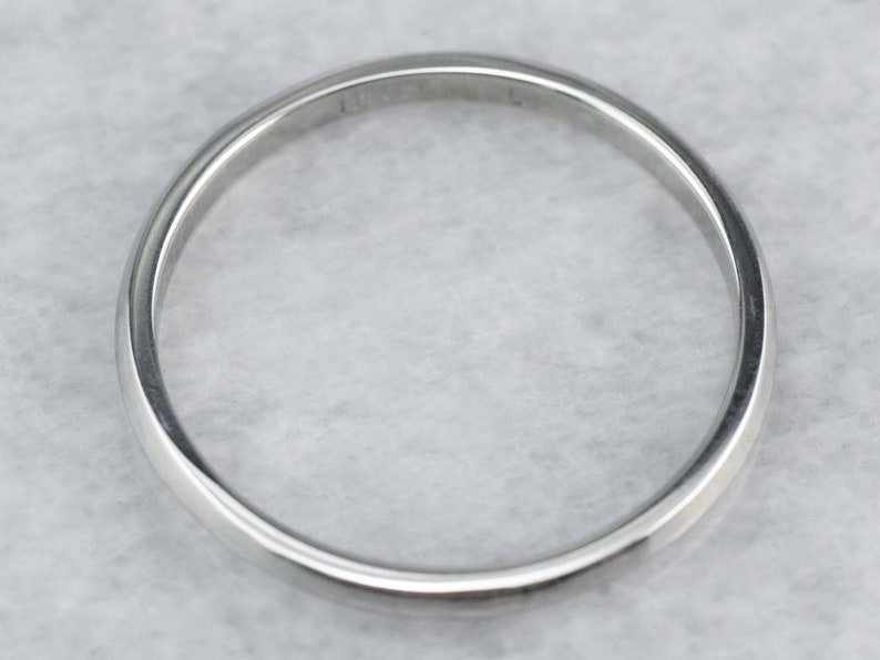May include: A plain silver wedding band with a smooth, rounded surface.
