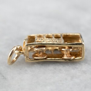 May include: Gold charm in the shape of a vintage train engine. The charm is detailed with wheels and windows. The charm has a loop for attaching to a necklace or bracelet.