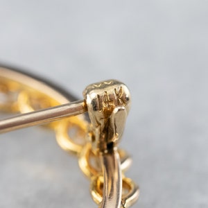 Puede incluir: Primer plano de un pendiente de oro con una marca de 14K. El pendiente es un aro con un delicado dise&ntilde;o de cadena.