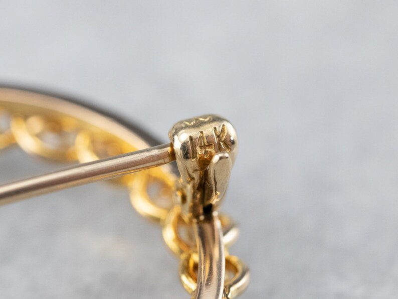 Puede incluir: Primer plano de un pendiente de oro con una marca de 14K. El pendiente es un aro con un delicado dise&ntilde;o de cadena.