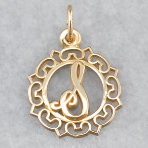 May include: A gold-toned pendant featuring a cursive letter 'S' in a circular frame with a decorative filigree design.