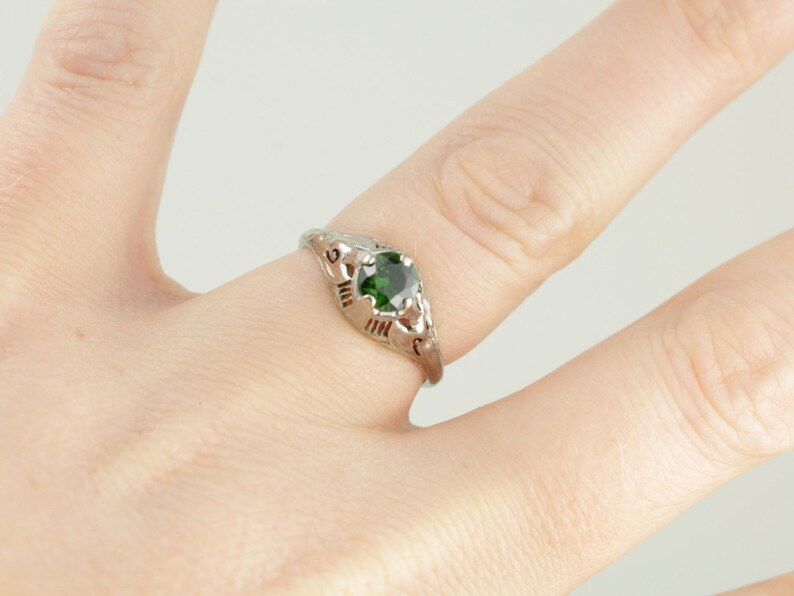 May include: A silver ring with a green gemstone set in a delicate filigree design.