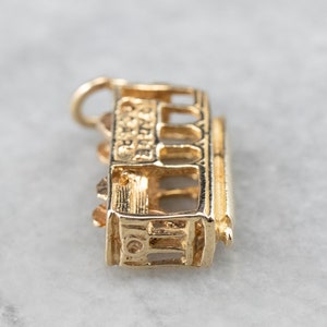 May include: Gold charm of a San Francisco cable car, a popular souvenir for visitors to the city.