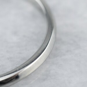 May include: Close-up of a silver wedding band with a smooth, rounded edge.