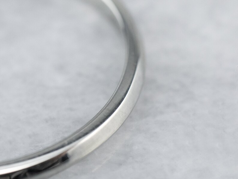May include: Close-up of a silver wedding band with a smooth, rounded edge.