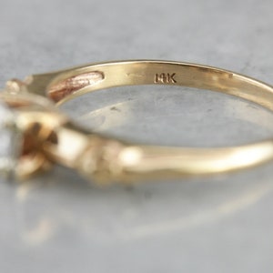 May include: A gold ring with a single diamond set in a twisted band. The ring is marked "14K" on the inside.