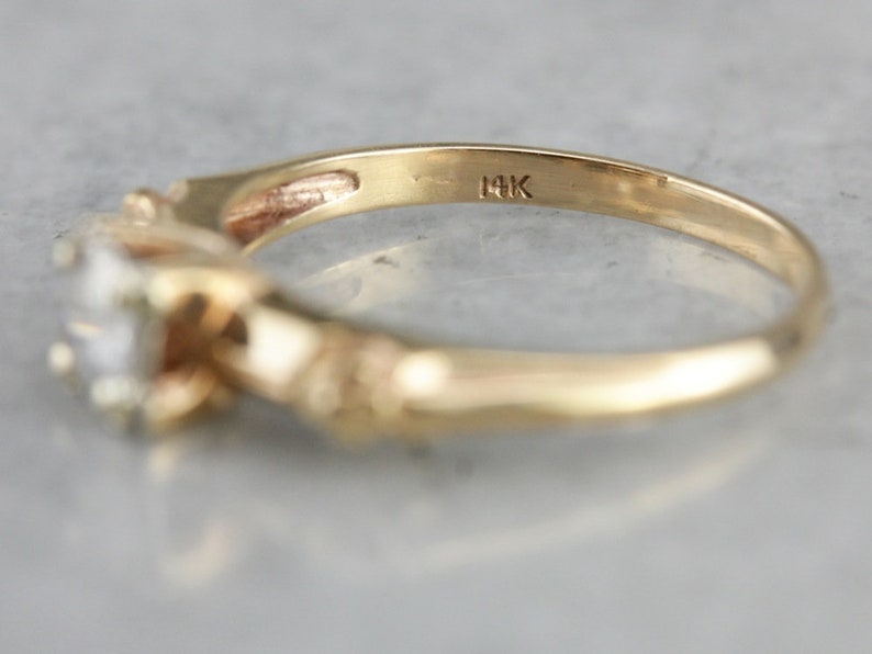 May include: A gold ring with a single diamond set in a twisted band. The ring is marked "14K" on the inside.