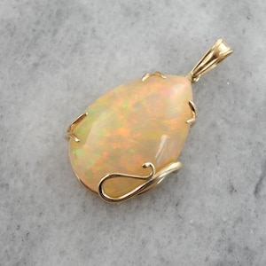 May include: A teardrop-shaped opal pendant set in a gold setting. The opal is a milky white color with flashes of iridescent color.