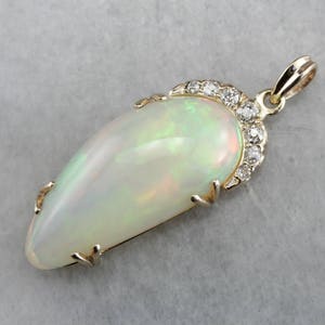 May include: A gold pendant featuring a large, white opal with a teardrop shape. The opal is surrounded by a halo of small, sparkling diamonds.
