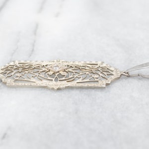 May include: A delicate gold pendant with a filigree design and a single diamond in the center.