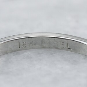 May include: Close-up of the inside of a silver band with the inscription "18K GABRIEL" on the inside.