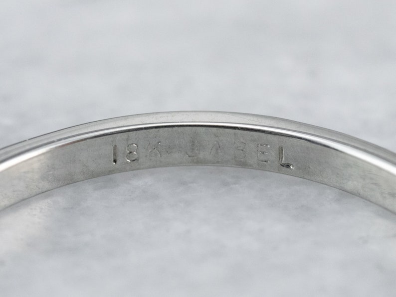 May include: Close-up of the inside of a silver band with the inscription "18K GABRIEL" on the inside.
