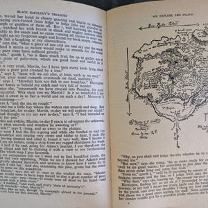 May include: Open book pages with text and a detailed, hand-drawn map of an island. The map includes geographical features, compass directions, and handwritten annotations, suggesting exploration and adventure.