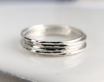May include: Set of four silver hammered stacking rings. The rings are thin and delicate, with a hammered texture that gives them a unique look.
