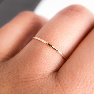 May include: A thin gold band ring with a hammered texture.