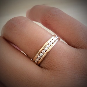 May include: A set of two thin gold and silver rings with a hammered texture. The rings are stacked on each other and have a row of small, round beads on the silver ring.