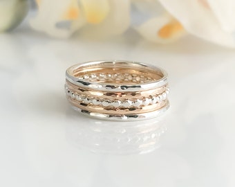 Può includere: Un set di cinque anelli impilabili in argento e oro rosa. Gli anelli sono testurizzati e hanno un design a perline.