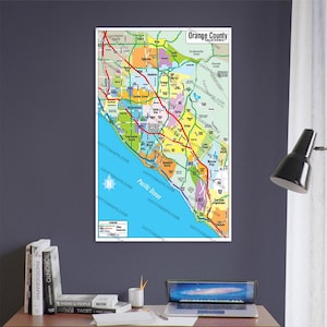 Puede incluir: Un mapa colorido del condado de Orange, California, con los límites de las ciudades y las carreteras principales resaltadas. El mapa está impreso en papel blanco y tiene un borde azul. Las palabras "Orange County" y "California" están impresas en negro en la parte superior del mapa.