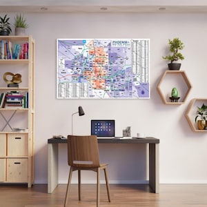 Könnte beinhalten: Eine gerahmte Karte des Großraums Phoenix, die Postleitzahlen und Stadtgrenzen zeigt. Die Karte ist überwiegend lila, orange und weiß, mit dem Titel "Phoenix Metro Area Zip Code Map" oben. Die Karte hängt an einer weißen Wand über einem Schreibtisch.