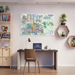 May include: A map of Bakersfield, Kern County, CA. The map is printed on white paper and has a green background. The map shows the different neighborhoods and streets in Bakersfield. The map is framed and hanging on a white wall.