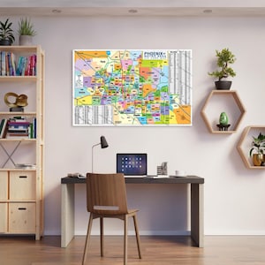 Könnte beinhalten: Eine farbenfrohe Karte der Metropolregion Phoenix, Arizona, die die verschiedenen Städte und Gemeinden in der Region zeigt. Die Karte ist auf weißem Hintergrund gedruckt und in einem schwarzen Rahmen gerahmt. Die Karte hängt an einer weißen Wand in einem Heimbüro.
