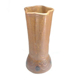 May include: A brown ceramic vase with a textured surface and a flared base. The vase has a unique, wavy rim and a decorative pattern of dark brown spots.