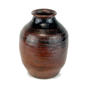 May include: A small, brown ceramic vase with a dark brown glaze. The vase has a rounded body and a narrow neck.