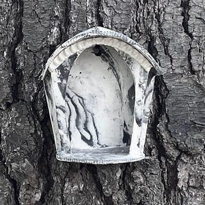 Peut inclure: Une petite niche murale arquée à façade ouverte avec une finition marbrée noire et blanche. La structure présente un sommet incurvé avec un bord nervuré et une base plate, conçue pour contenir de petits objets dans son espace intérieur creux.