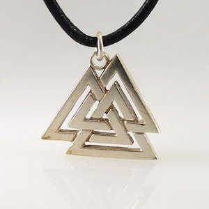 Puede incluir: Collar con colgante de plata en forma de triángulo con un diseño de nudo celta. El colgante está en un cordón de cuero negro.