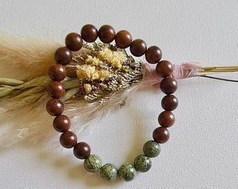 Pode incluir: Um bracelete de contas de madeira marrom com contas salpicadas de verde e marrom.