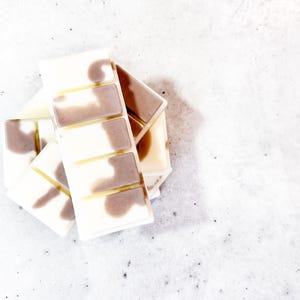 May include: A stack of wax melts in a white and brown marbled pattern. The wax melts are in a rectangular shape with four sections.
