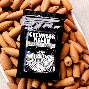 May include: A black pouch with a white graphic of waves and a boat. The pouch contains brown incense cones and the text "Cucumber Melon Incense Cones".