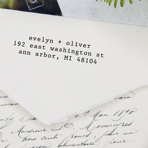 May include: A stationery set featuring a white envelope with the address "evelyn + oliver, 192 east washington st, ann arbor, MI 48104" printed in black. A black stamp and handwritten letter are also visible.
