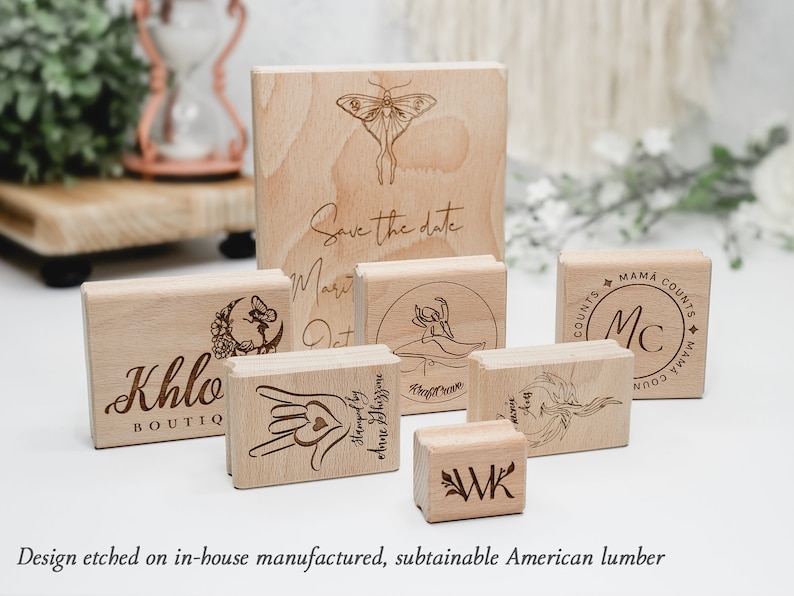 May include: A collection of eight wooden stamps with various designs, including a butterfly, a moon, a heart, a wreath, and initials. The stamps are made of natural wood and have a rustic look. The text "Save the date" is engraved on one of the stamps.