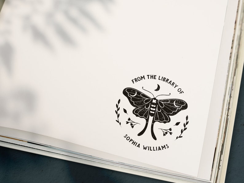May include: A black and white illustration of a moth with a crescent moon above it. The text "From the Library of Sophia Williams" is written in a circle around the moth.