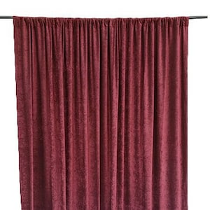 Könnte beinhalten: Burgunderfarbener Samtvorhang für die Bühne mit einem strukturierten Muster. Der Vorhang ist an einer schwarzen Stange aufgehängt.