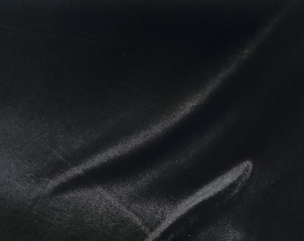 May include: Black fabric with a smooth, silky texture. The fabric is draped and has a slight sheen.