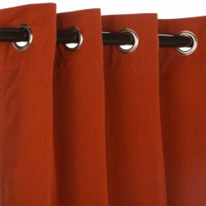 Pu&ograve; includere: Primo piano di quattro pannelli di tenda color ruggine con occhielli metallici. I pannelli sono appesi a un'asta marrone scuro. Il tessuto ha un aspetto strutturato e le tende sono parzialmente chiuse.