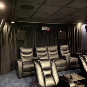 May include: A home theater room with black leather reclining chairs, black curtains, and a projector on the ceiling.