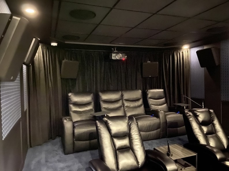 May include: A home theater room with black leather reclining chairs, black curtains, and a projector on the ceiling.