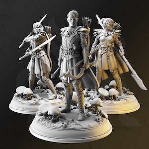 Puede incluir: Tres figuras en miniatura de personajes de fantasía, pintadas en un esquema de colores blanco, gris y negro. Las figuras están posadas de forma dinámica, con espadas y arcos en la mano. Las figuras están de pie sobre una base con un diseño de hongo.