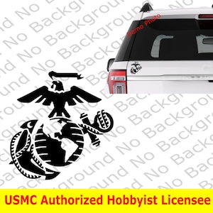 May include: Black and white decal of the US Marine Corps emblem, featuring an eagle, globe, and anchor. The decal is displayed on the back window of a white SUV. The text "USMC Authorized Hobbyist Licensee" is displayed below the emblem.