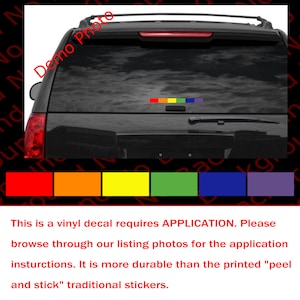 May include: A rainbow vinyl decal with the colors red, orange, yellow, green, blue, and purple. The decal is applied to the back window of a black SUV. The decal is a vinyl sticker that requires application.