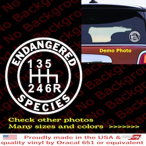 May include: White vinyl decal with a black and white gear shift pattern and the words "Endangered Species" around the outside. The decal is on a red car.