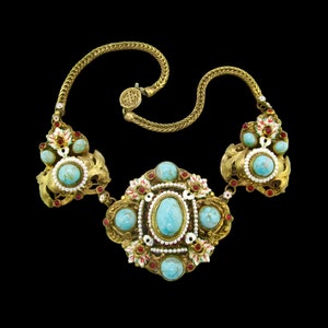 Peut inclure: Un collier en or avec un grand pendentif turquoise central et de plus petites pierres turquoise. Le collier est d&eacute;cor&eacute; d'&eacute;mail rouge et blanc et de petites perles.
