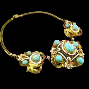 Peut inclure: Un collier en or avec des pierres turquoise et rouges. Le collier a un grand pendentif orn&eacute; avec un motif floral.